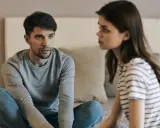 Un homme et une femme se regardent, assis sur un lit, dans une ambiance tendue.