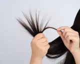 Mani che esaminano ciocche di capelli fini che si spezzano, mostrando la fragilità e la necessità di cura.