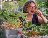 Frau genießt frisch gepflückte Erdbeeren aus ihrem Garten. Die Freude am Erdbeeren pflanzen ist ihr ins Gesicht geschrieben.