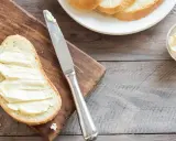 Brot mit Butter bestrichen, daneben eine Schale mit Butter und ein Messer. Ob Butter oder Margarine, beides enthält Cholesterin.