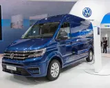 Niebieski kamper elektryczny e-Crafter podłączony do ładowarki na stoisku Volkswagena.