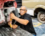 Mechanik w okularach ochronnych pracuje przy samochodzie. Sprawdza stan podłużnicy, szukając informacji o wymiana podłużnicy cena.