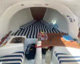 Intérieur du first 210, avec banquettes rayées bleu et blanc, réchaud, outils et bidon d'eau. Prêt pour l'aventure !