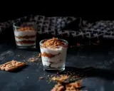 Deux verrines de tiramisu speculoos, garnies de miettes croustillantes. Un biscuit speculoos repose à côté.