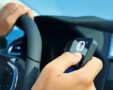 Fahrer hält ein Gerät mit Bluetooth-Symbol, während er das Lenkrad en 300 328 bedient.