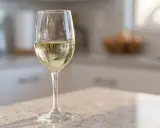 Ett glas med torrt vin står på en bänkskiva i ett kök.