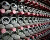 Staubige Wein­fla­schen, die auf­ge­reiht lagern. Die "crianza bedeutung" liegt in der Reife und dem Ausbau, der dem Wein seinen Charakter verleiht.