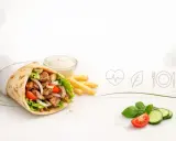 Kebab w tortilli z frytkami, sosem i warzywami, obok ikony serca i liścia.
