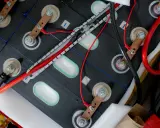 Zestaw ogniw tworzących baterię do samochodu elektrycznego, połączonych miedzianymi listwami i przewodami.