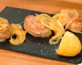 Tiernos medallones de carne al jerez, cubiertos con cebolla caramelizada y acompañados de una porción de patata.