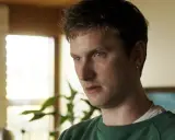 Mikkel Boe Følsgaard, en ung man med grönt linne, tittar bort. Bakom honom syns en växt och ett fönster.