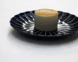 Un cylindre blanc, saupoudré d'or, sur une assiette bleue. Une idée de quoi manger à Paris pour une expérience culinaire unique.