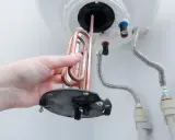 Mano retirando resistencia de cobre para saber como limpiar un termo por dentro.