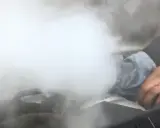 Sale humo del motor y huele a quemado. Una mano con un trapo intenta arreglar la avería.