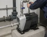 Installazione di una pompa per risolvere la pressione acqua bassa. Un tecnico regola le valvole.
