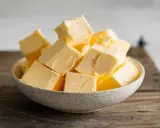 Ein Schälchen voller goldgelber Butterwürfel, bereit für den Einsatz in der Küche. Butter liefert auch etwas Calcium.