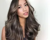 Mujer con pelo negro color caramelo, con ondas suaves y reflejos luminosos.