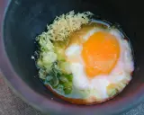 Ein perfekt zubereitetes Onsen-Ei mit Frühlingszwiebeln und geriebenem Ingwer in einer dunklen Schüssel.