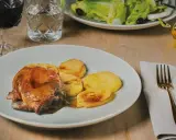 Plato de carne asada con patatas, un ejemplo de comida típica de Huesca. Acompañado de ensalada, vino tinto y aceite de oliva.