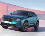 Nowy Peugeot E-3008 2021 w turkusowym kolorze, zaparkowany przed nowoczesnym budynkiem z różowymi akcentami.