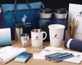 Zestaw eleganckich gadżetów firmowych: torba, kubki, termosy, notesy i długopisy. Idealny reklamowy drobiazg dla klientów.