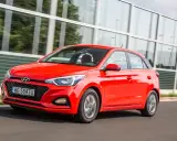 Czerwony Hyundai i20 1.2 benzyna w ruchu, z nowoczesną atrapą chłodnicy i światłami.