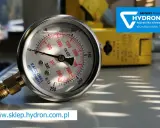 Manometr służy do pomiaru ciśnienia w układach hydraulicznych. Widoczny jest precyzyjny przyrząd z tarczą w barach i psi.