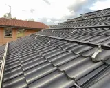 Solpaneler monteras på taket med hjälp av robusta aluminium skenor. Takpannorna är mörka och vågformade.