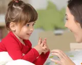Ein kleines Mädchen und eine Frau sprechen liebevoll miteinander. Dies zeigt, welche erziehungsstile es gibt, wie z.B. den autoritativen Stil.