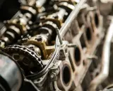 Zbliżenie na mechanizm rozrządu silnika samochodowego. Widoczny jest łańcuch rozrządu i koła zębate, które mogą wskazywać na objawy kończącego się rozrządu.