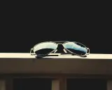 Okulary przeciwsłoneczne typu aviator leżące na drewnianej powierzchni.