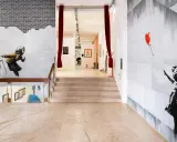 Banksy Lissabon: ikonische Werke wie das Mädchen mit dem roten Ballon und die wegspritzende Frau zieren die Wände einer Ausstellung.
