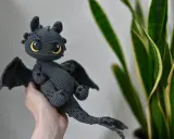 Adorable dragón amigurumi gris con ojos amarillos brillantes. ¡Encuentra el dragon amigurumi patron gratis en español para crear el tuyo!