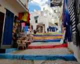 Bunte Treppe in Tanger, wo Frauen in bunten Gewändern Souvenirs verkaufen.