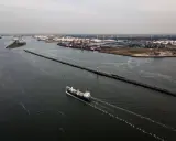 Una nave solca le acque di quello che è il più grande porto d'Europa, con industrie e serbatoi sullo sfondo.