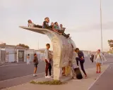 Kids gather on a unique bus stop structure, a scene that could be featured in a Belfast photo festival, capturing everyday life.