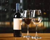 Une bouteille de vin rouge et deux verres, dont un partiellement rempli. Combien de verre dans une bouteille de vin ? La réponse est dans le plaisir de la dégustation.