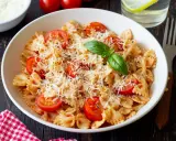 Pyszny makaron farfalle z pomidorkami koktajlowymi i parmezanem, idealny na kolację.
