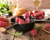 Préparation pour comment faire une fondue bourguignonne : dés de bœuf sur des brochettes, prêts à être plongés dans l'huile chaude.
