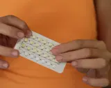 Manos sostienen un blíster de pastillas anticonceptivas. Me he quitado el anillo y no me baja la regla, ¿será por esto?