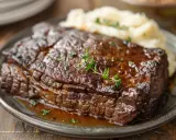 Un plat de jarret de boeuf braisé, tendre et savoureux, servi avec une purée de pommes de terre crémeuse et garni de thym frais.