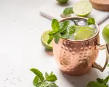 Erfrischender Moscow Mule in Kupferbecher mit Limettenscheiben, Minze und Eis. Perfekt für warme Tage und verschiedene rum sorten.