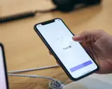 Dłoń trzyma iPhone'a z włączonym ekranem Face ID.
