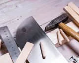 Herramientas para trabajar la madera: sierra, martillo, regla y tacos de madera listos para un proyecto.