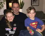 Marcus Oscarsson med sin familj, dottern och sonen sitter glatt i soffan.