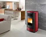 Estufa de pellets roja y negra en un salón moderno, mostrando las ventajas de la biomasa para un hogar cálido y sostenible.