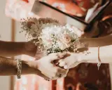 Manos entrelazadas sosteniendo un ramo de flores, un momento íntimo de los rituales boda civil.
