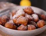 Un bol rempli de beignets dorés, saupoudrés de sucre glace. Parfait pour une recette beignet moelleux rapide.