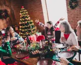 Familia celebrando Navidad en España con niños. Árbol decorado, mesa puesta y regalos. ¡Un plan perfecto donde ir en navidad en españa con niños!