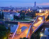 Most Wrocławia w niebieskiej godzinie. Most Grunwaldzki i ruch uliczny tworzą świetlne smugi na tle miasta.